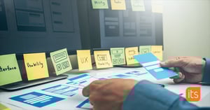 Person som sätter upp post-it-lappar på en vägg med termer för användbarhet och tillgänglighet.
