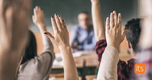 pupils with the hands raised to answer a question in the classroom