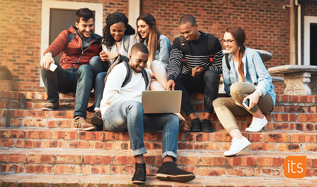 Students sitting on stairs looking at laptop