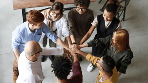 Top-down view of a diverse group of people placing their hands together in unity