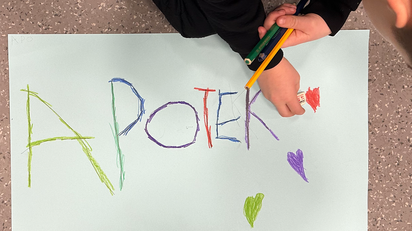 child writing on paper with crayons