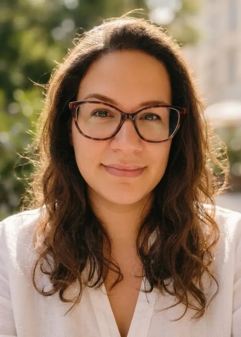 Chrystel Sinclair Brandt, wearing glasses and a white shirt, looking at the camera smiling. 