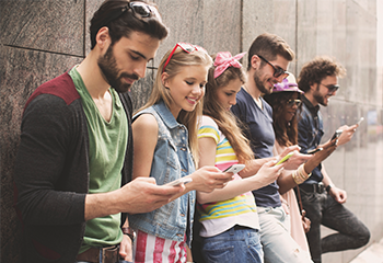 Five students looking at their phones while smiling