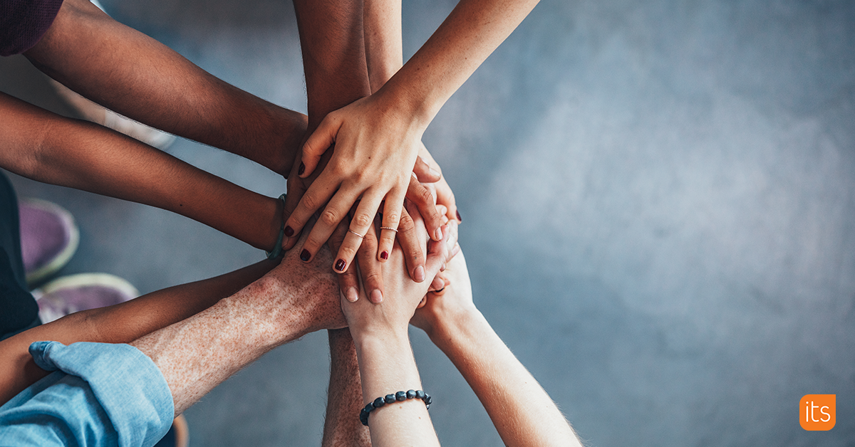 Photo of a group of hands stacking on top of eachother for team spirit.