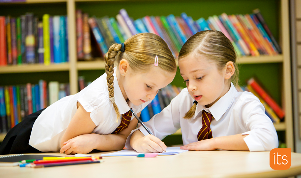 two girls, one of them is writing on paper